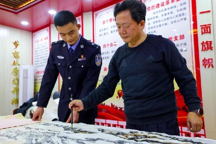 图为移民管理警察向书法家学习书画技巧 梅俊豪摄