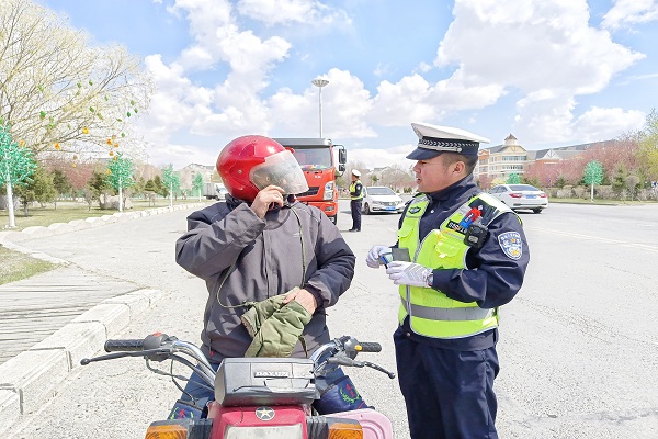 民警在路面排查骑乘摩托车人员 并进行安全提示