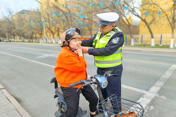 民警为骑乘电动车人员佩戴安全头盔