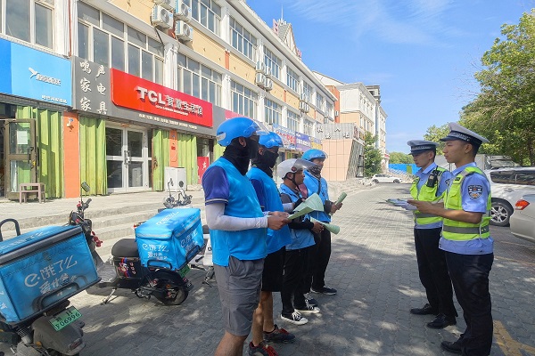民警通过发放宣传单的方式为外卖骑手讲解道路交通安全知识
