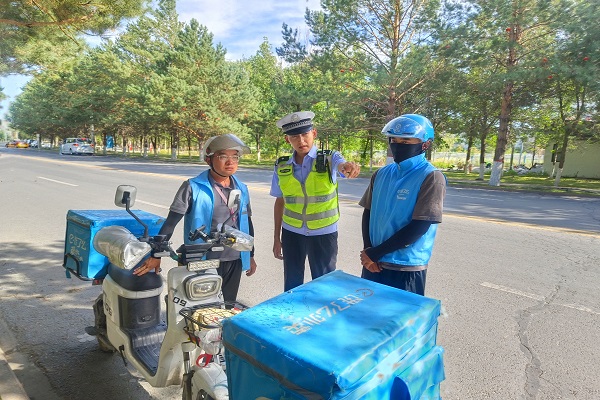 民警为外卖骑手在道路上讲解打击通安全知识