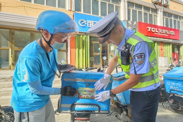 民警为外卖骑手张贴拒绝酒驾 平安出行宣传标语