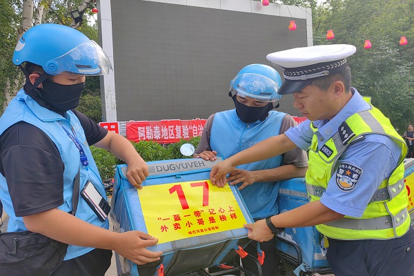 哈巴河县公安局交警大队大队长张龙为快递小哥张贴放大号 确保交通安全1 (2)