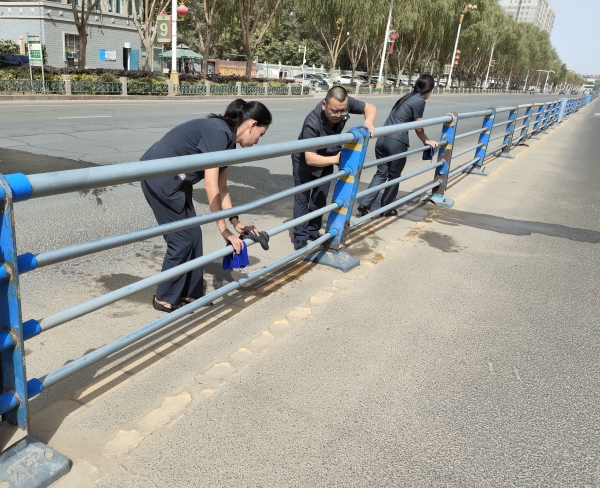洛浦县人民法院干警在认真擦拭马路隔离栏。秦国泰摄.jpg