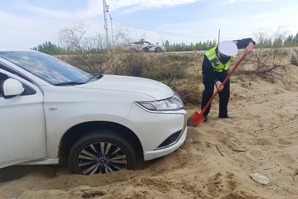 执勤民警对车辆底部沙土进行铲挖