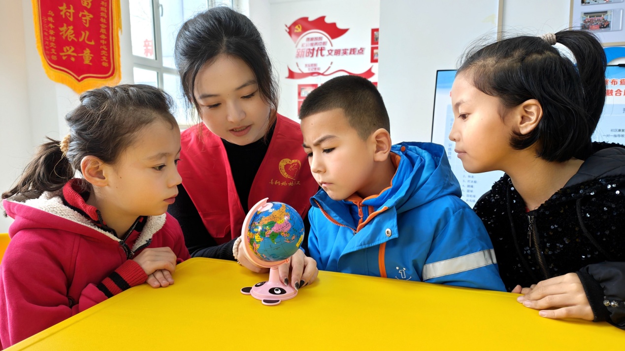 C:\Users\Administrator\Desktop\新建文件夹 (4)\新建文件夹 (3)\12月16日，察布查尔镇石榴籽小课堂内，来自盐城师范学院城市与规划学院的支教大学生志愿者姚钰菁（左二）用地球仪讲解地理课。华岩明摄a401705973e359889d17aa49914735a.jpg