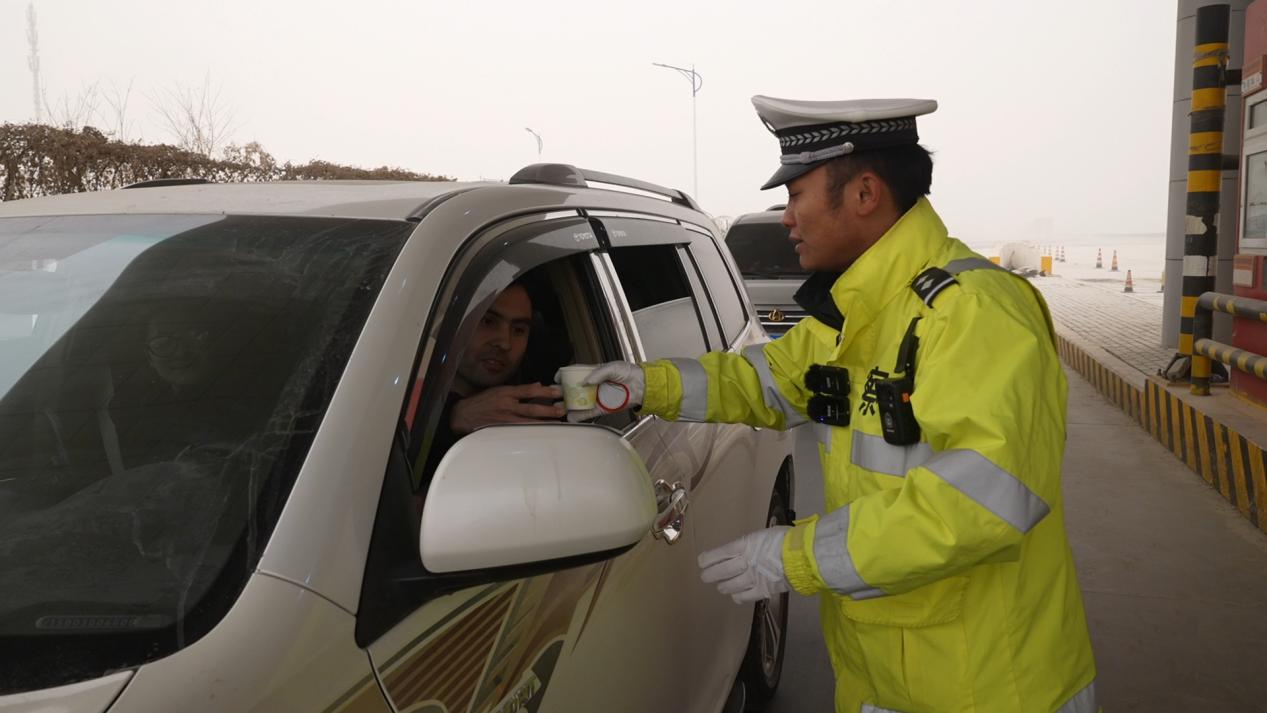 交警给过往车辆进行温馨提示并送上热水