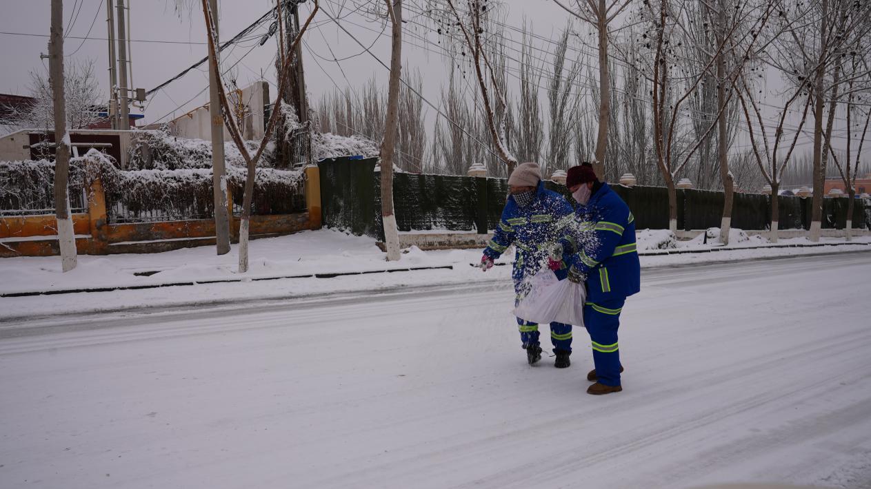 环卫工人在易滑易摔点位进行撒盐除冰