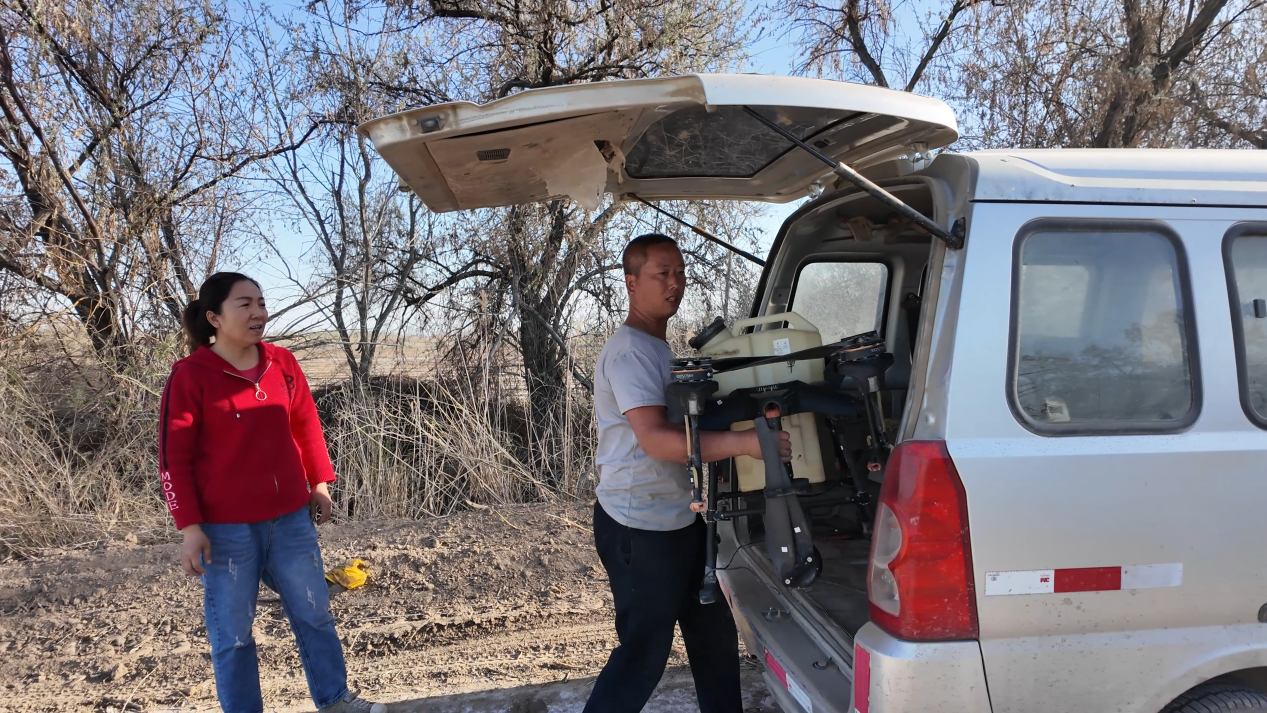 图为:4月23日,狄明东和妻子正在从车上卸下农用植保无人机。芦文涛 摄