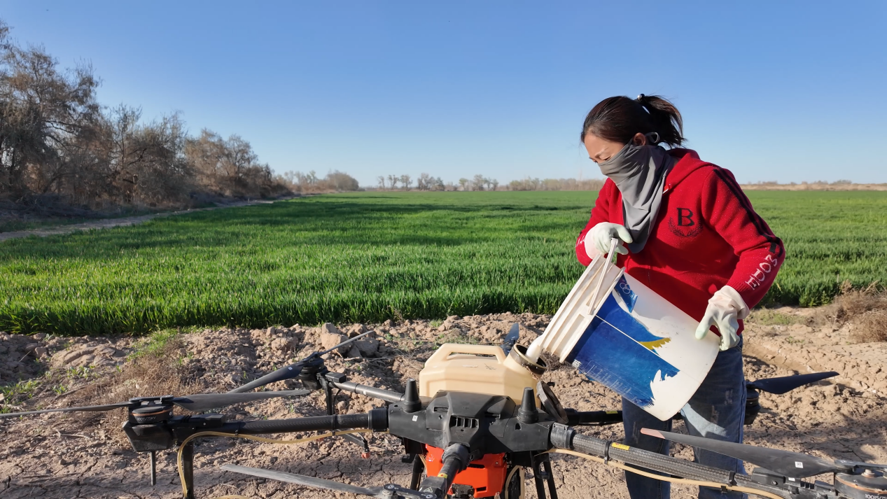 图为:4月23日,李魏正在给农用植保无人机加药。芦文涛 摄