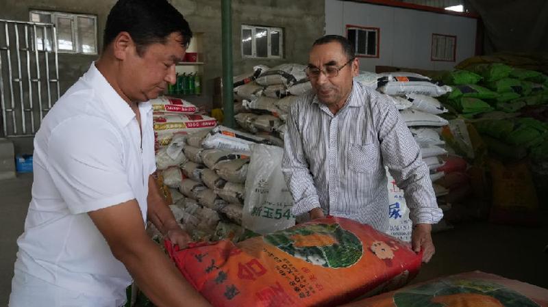 吐外特乡种子代销店负责人在仓库里搬化肥