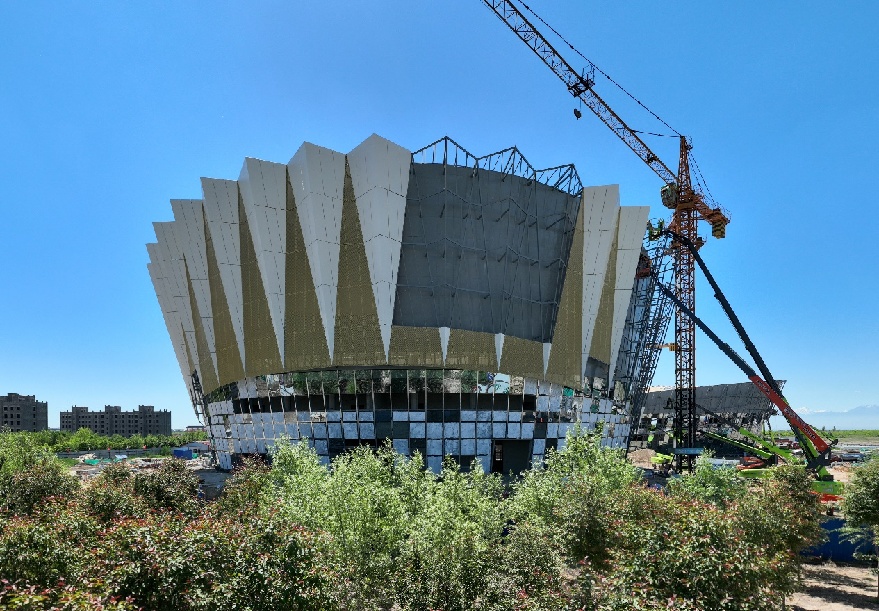 5月28日，七师胡杨河市职工文化体育中心建设项目现场，工人乘坐高空作业车进行外立面幕墙装饰装修作业。该项目自2024年4月初复工以来，严格把控各个施工细节质量，每一道工序验收合格后，进行下一步施工。目前现场稳定施工作业人员一百余人，配备20余台高空作业车辅助施工。刘笑天摄 (2)