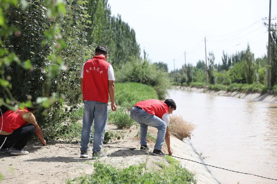阿卜杜热合曼·阿卜力孜和同事在水渠边巡逻。