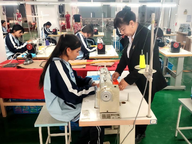 县技工学校服装营销与制作专业教师正在指导学生缝纫技术
